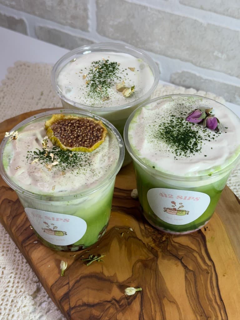 Three 412Sips matcha drinks with cold foam on a wooden serving board