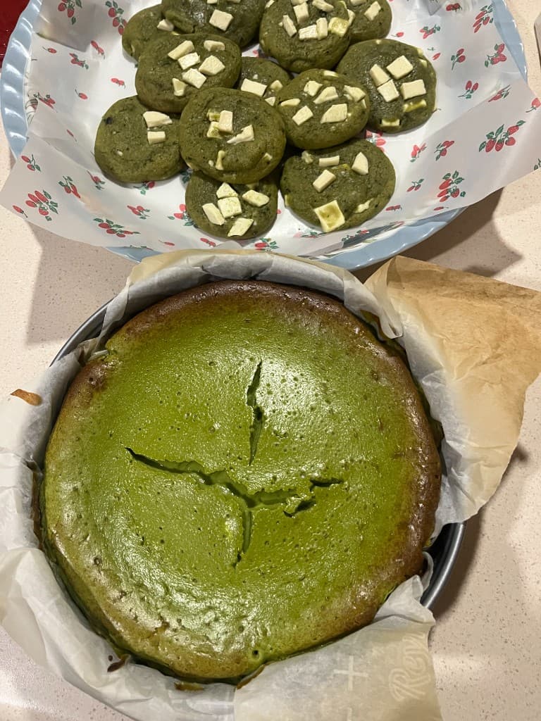 Matcha basque burnt cheesecake in a tin and matcha white chocolate cookies on a plate